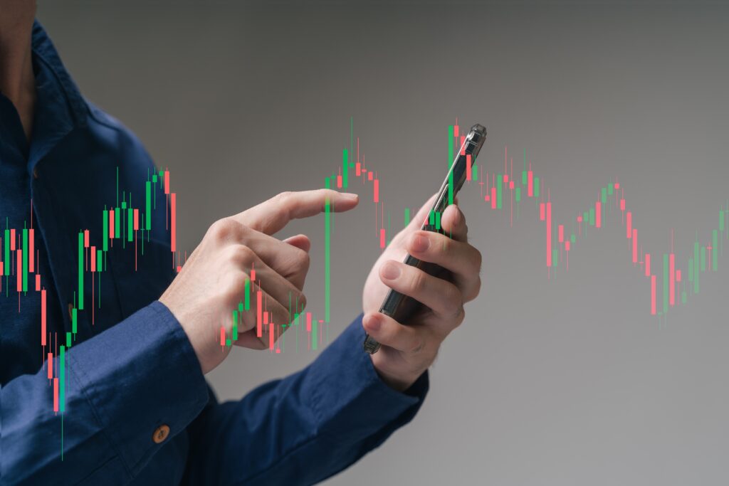 A trader doing copy trading on his mobile phone overlayed with trading candlesticks